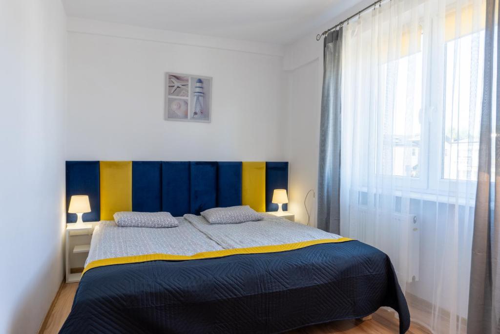 a bedroom with a blue and yellow bed and a window at Piast in Karwia