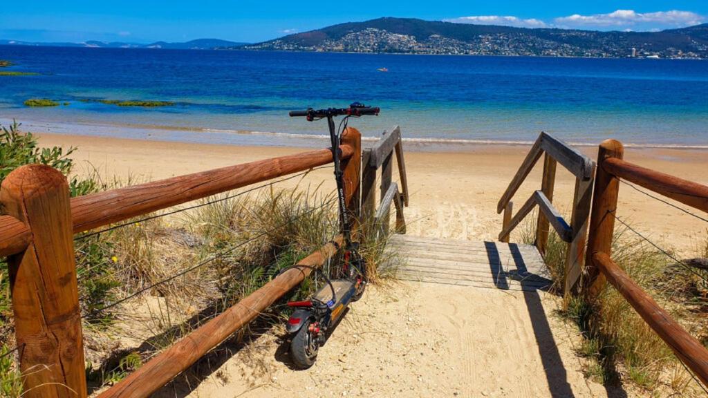a scooter is tied to a wooden rail on the beach at Beach House Bellerive Hobart Eastern Shore in Bellerive