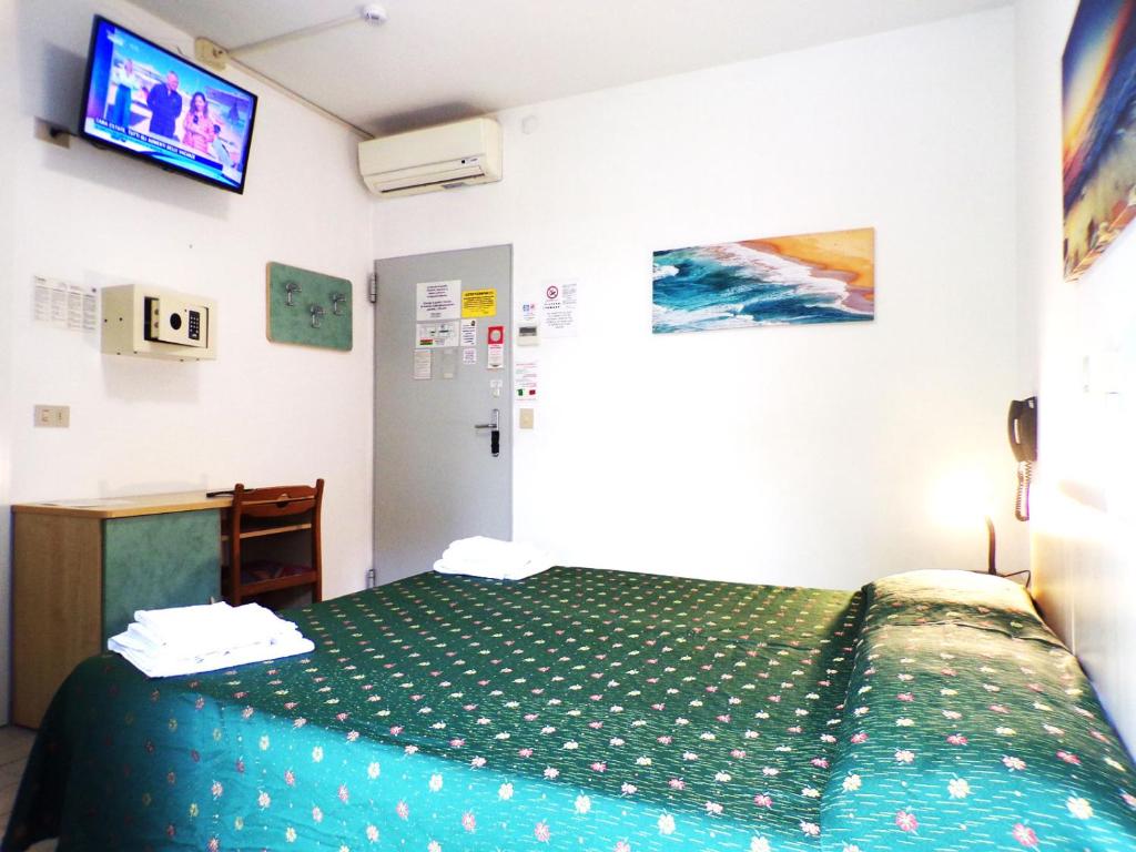 ミラノ・マリッティマにあるHotel Esedraのベッドルーム(緑色のベッド1台、テレビ付)