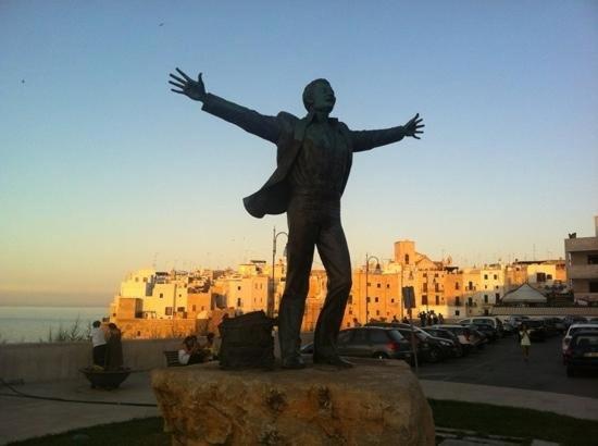 Une statue d'un homme avec ses bras dehors dans l'établissement La casa di Ginevra, à Polignano a Mare