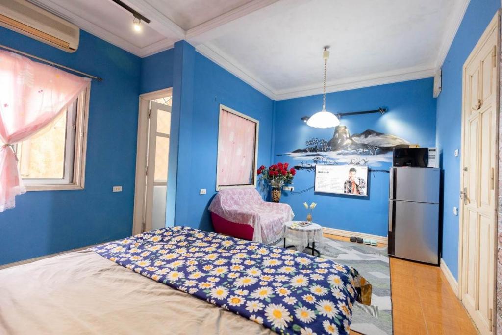een blauwe slaapkamer met een bed en een koelkast bij Hoankiem House in Hanoi