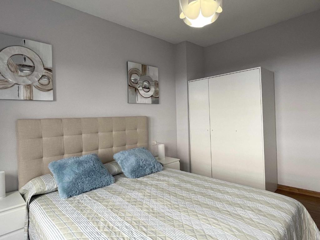 una camera con un letto con due cuscini blu di Paxarinos Playa by FlowHome a Gijón