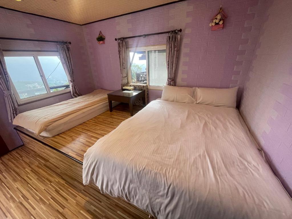 a bedroom with two beds and a purple wall at Emmanuel Farm House in Ren&#39;ai
