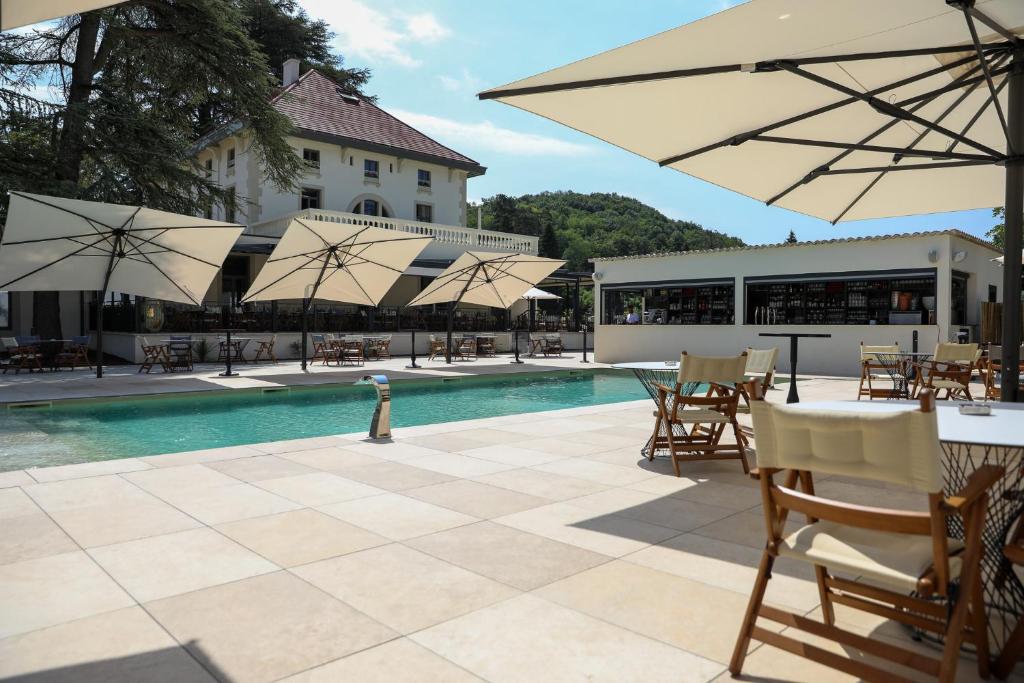 a pool with tables and chairs and umbrellas at Hôtel Les Séquoias in Ruy
