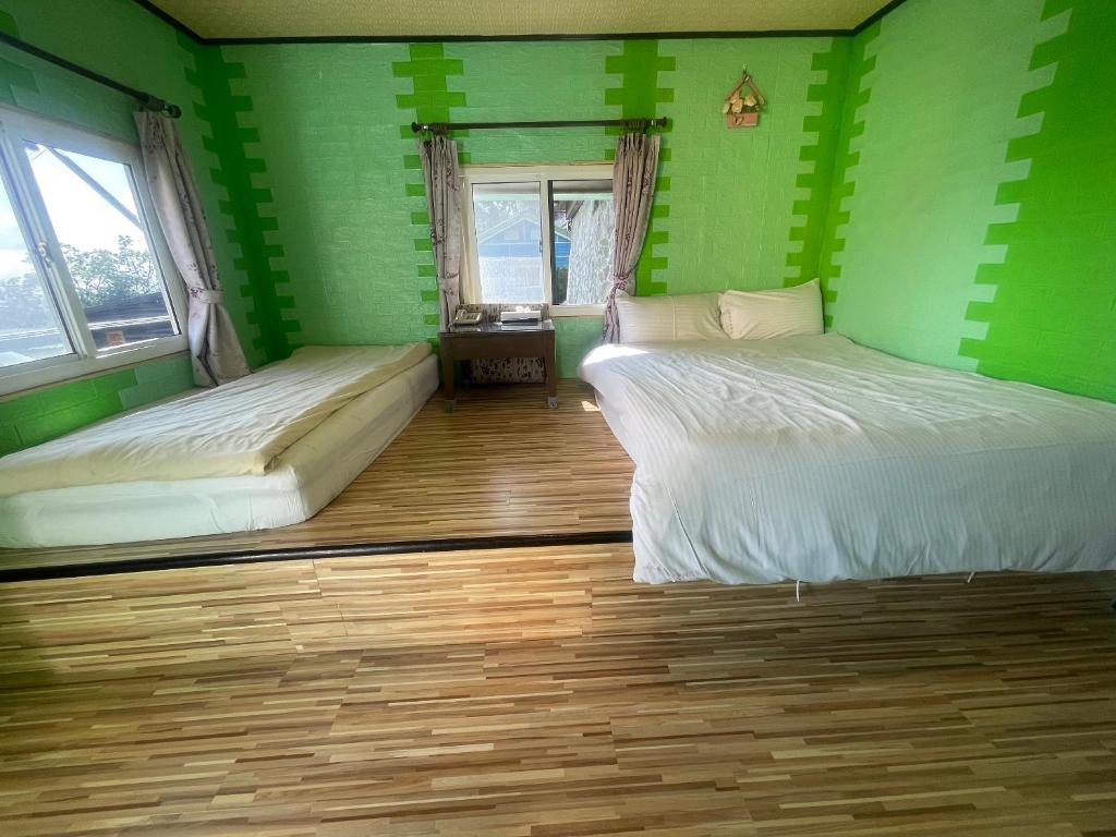 two beds in a room with green walls and wooden floors at Emmanuel Farm House in Ren&#39;ai