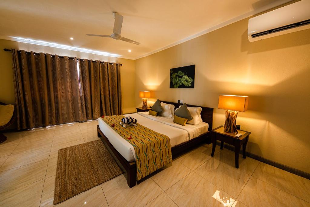 a bedroom with a bed and a table and two lamps at Anse Boudin Chalets & Villa in Praslin