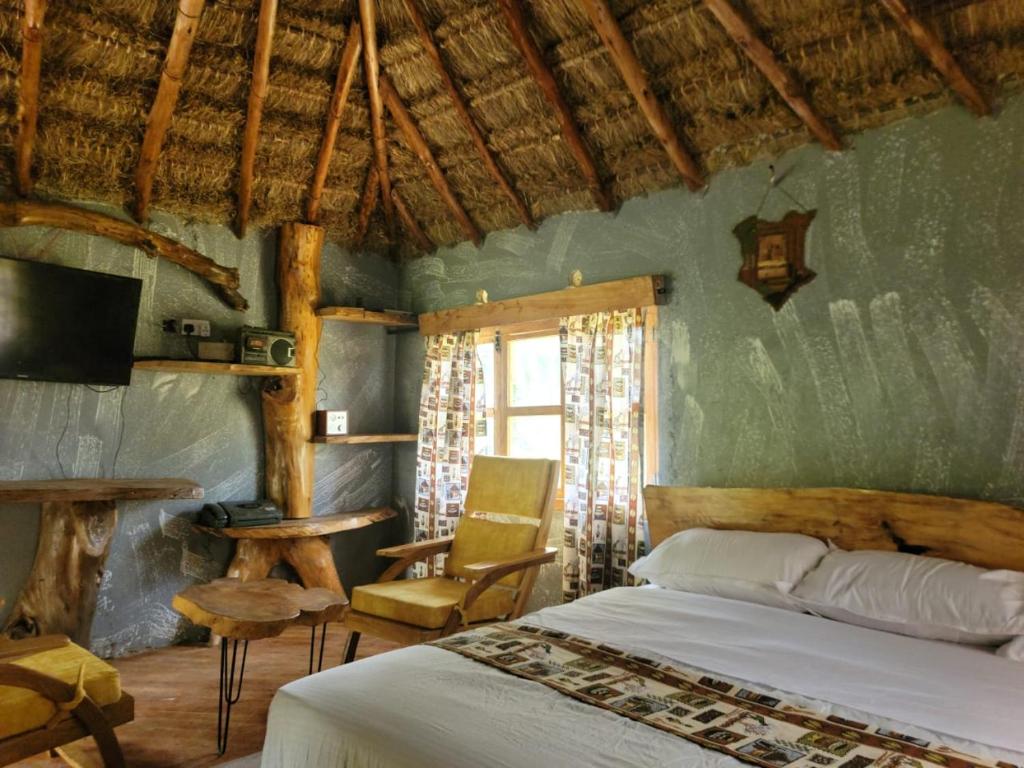 a bedroom with a bed and a table and a chair at Podocarpus cottages in Naro Moru