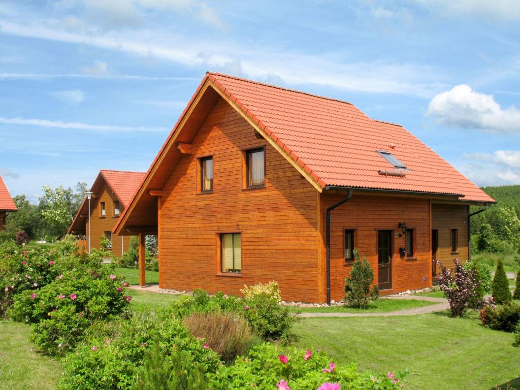 une maison en bois avec un toit orange dans l'établissement Holiday Home Auerhahn-2 by Interhome, à Hasselfelde