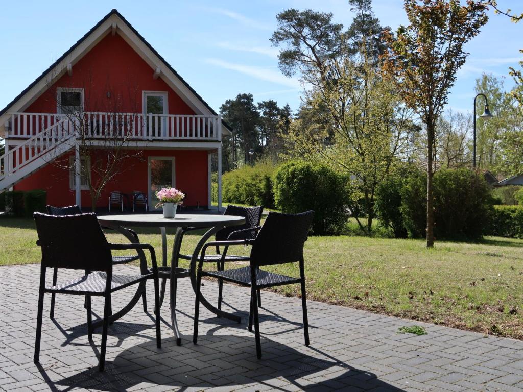 a table and chairs in front of a red house at Apartment Müritz Ferienpark Röbel-20 by Interhome in Röbel