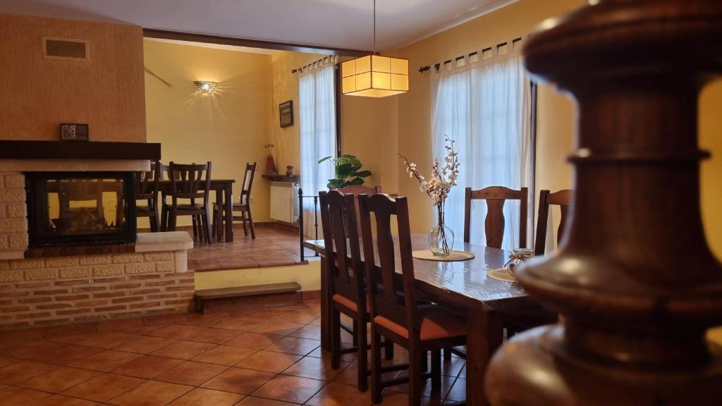 a dining room and living room with a table and a fireplace at Casa Rural La Posada de Santa Teresa in Pastrana