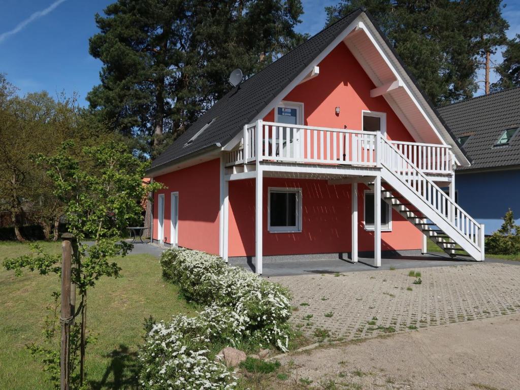 ein rotes Haus mit einer weißen Terrasse in der Unterkunft Apartment Müritz Ferienpark Röbel-21 by Interhome in Röbel