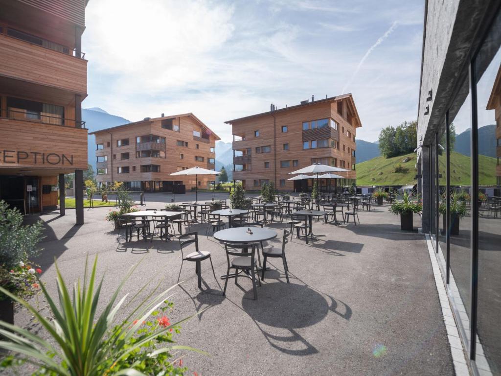 un patio al aire libre con mesas, sillas y edificios en Apartment Catrina Experience-1 by Interhome, en Disentis