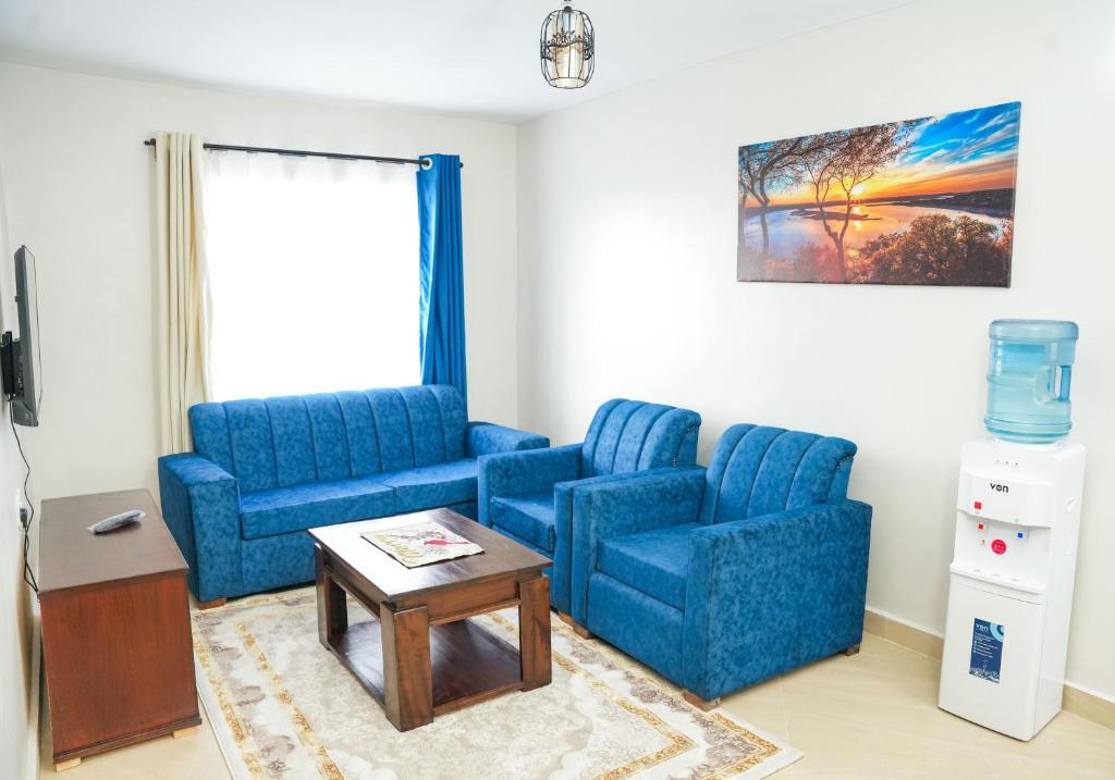 Kelly homes in Naivasha في نيفاشا: غرفة معيشة مع كرسيين ازرق وطاولة
