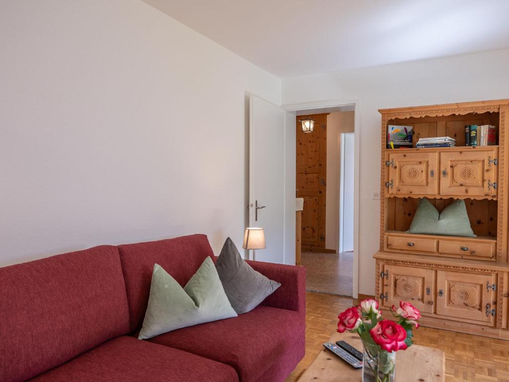 a living room with a red couch and a table with flowers at Apartment Chesa Muntarütsch by Interhome in Samedan