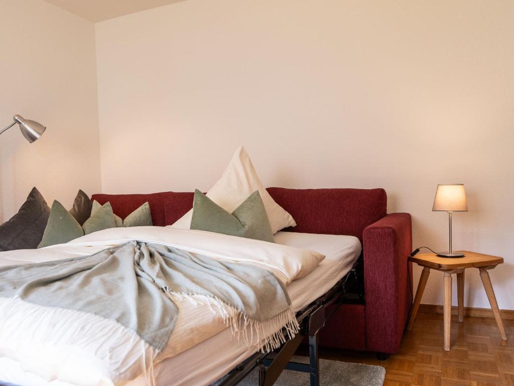 a living room with a red couch and a bed at Apartment Chesa Muntarütsch by Interhome in Samedan