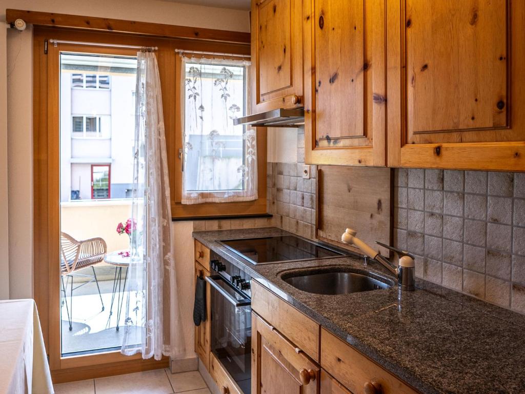 a kitchen with wooden cabinets and a sink and a window at Apartment Chesa Muntarütsch by Interhome in Samedan