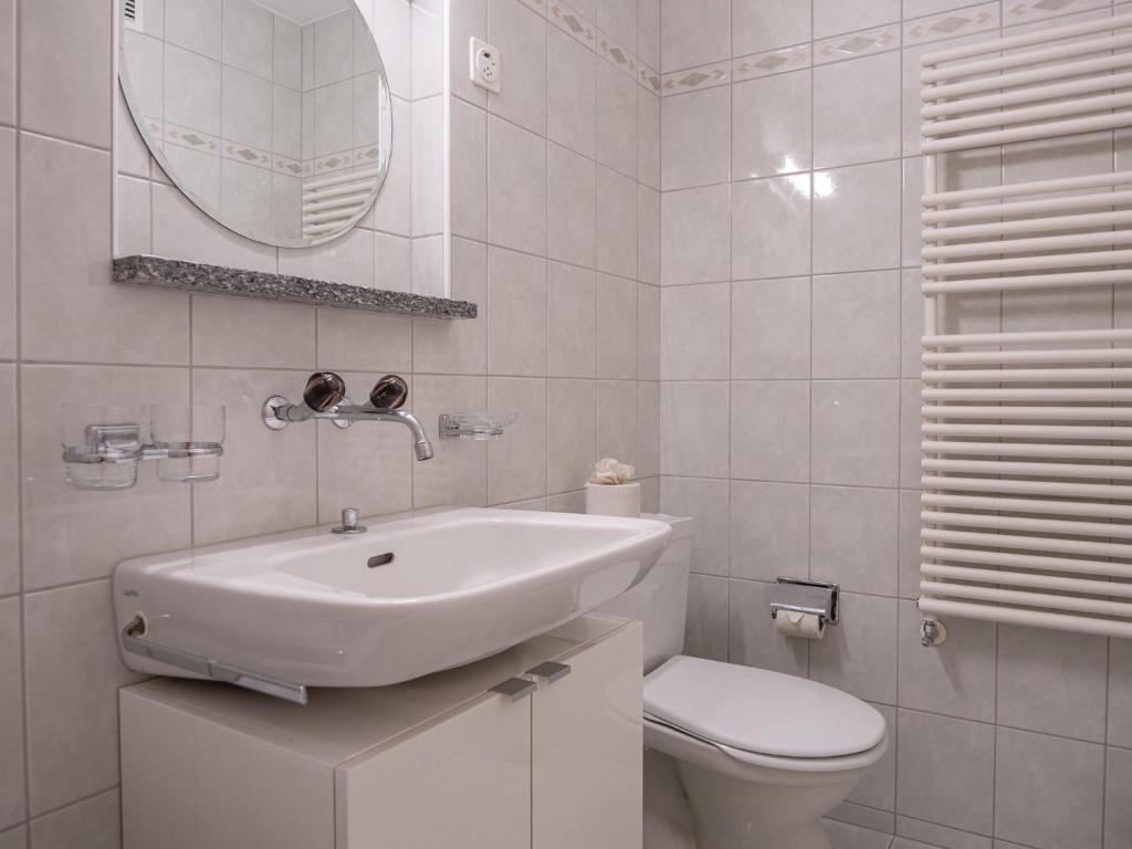 a white bathroom with a sink and a toilet at Apartment Chesa Muntarütsch by Interhome in Samedan