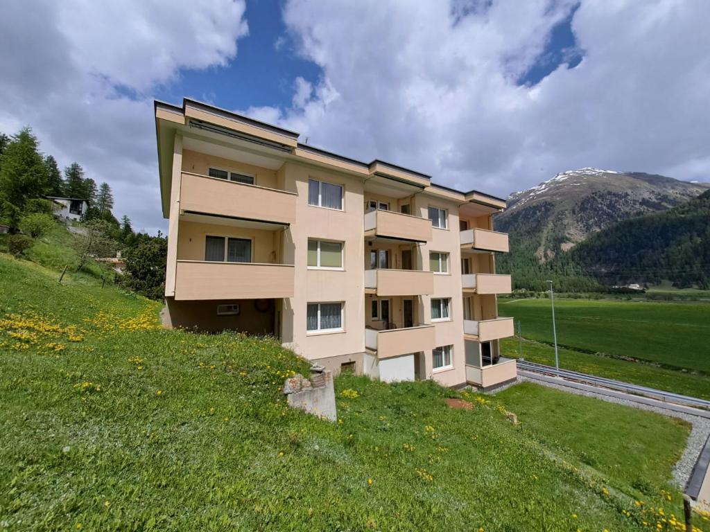 a building on a hill with a grassy field at Apartment Chesa Muntarütsch by Interhome in Samedan
