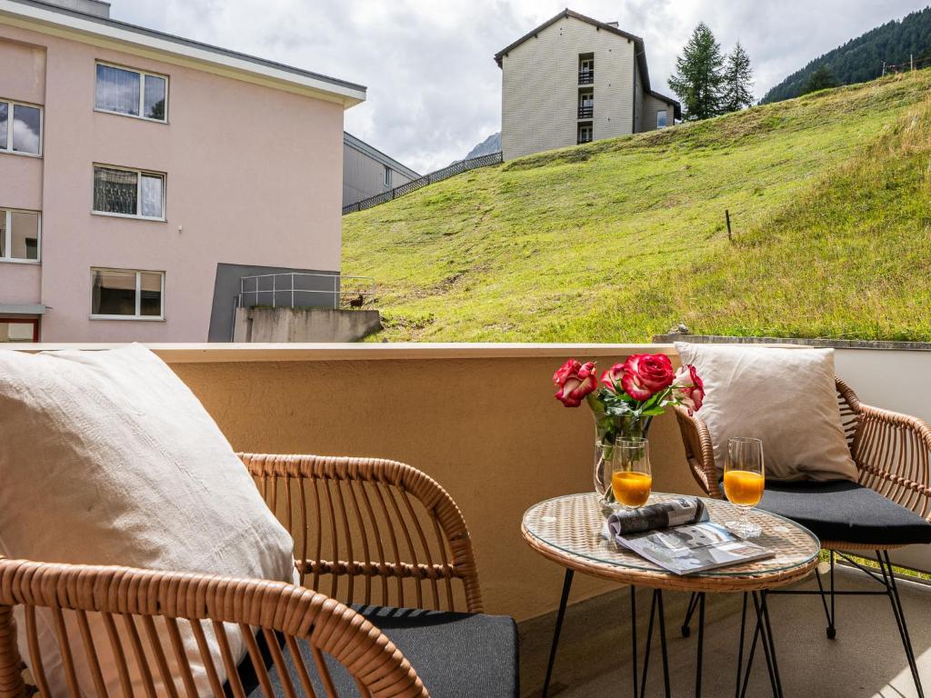 a table with two chairs and a vase of flowers on a balcony at Apartment Chesa Muntarütsch by Interhome in Samedan