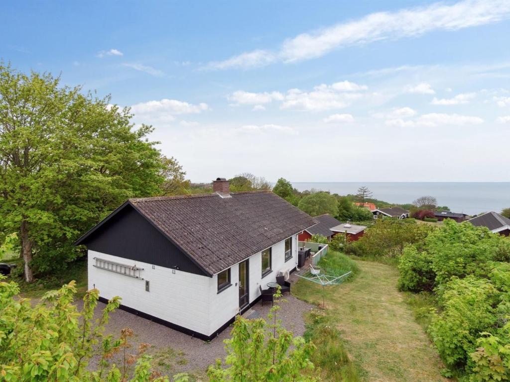 a white house with a black roof at Holiday Home Dika - 400m from the sea in Bornholm by Interhome in Hasle