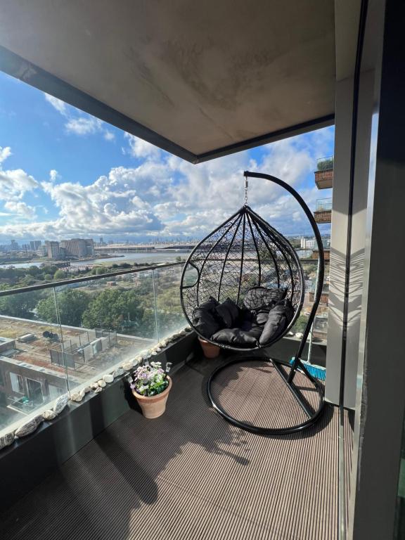 a swing on a balcony with a view of a city at Cityscape Serenity: 10th Floor Oasis near City Airport, Excel & 02 in London