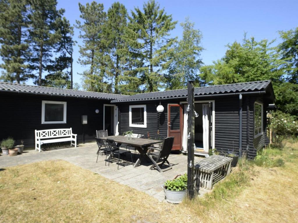 une cabine noire avec une table de pique-nique et une terrasse dans l'établissement Holiday Home Rami - from the sea in Sealand by Interhome, à Nykøbing Sjælland