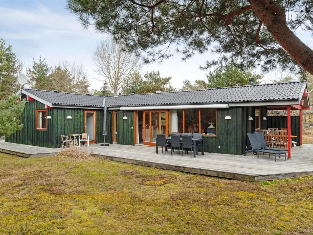 een groen huis met een terras en patio bij Holiday Home Nada - 200m from the sea in Bornholm by Interhome in Vester Sømarken