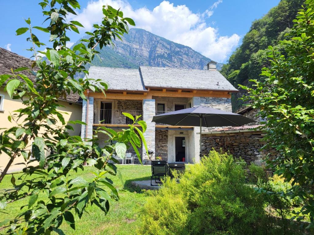 a stone house with an umbrella in the yard at Holiday Home Cà dal Leo by Interhome in Bignasco