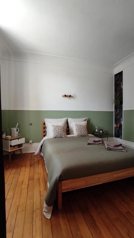 een slaapkamer met een groot bed met groene muren en houten vloeren bij Pavillon C.R in Isles-sur-Suippe