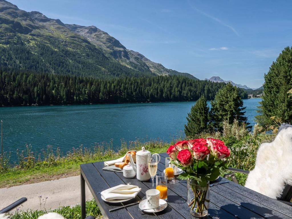 - une table de pique-nique avec un vase de fleurs et un lac dans l'établissement Apartment Chesa Anemona al Lej by Interhome, à Saint-Moritz