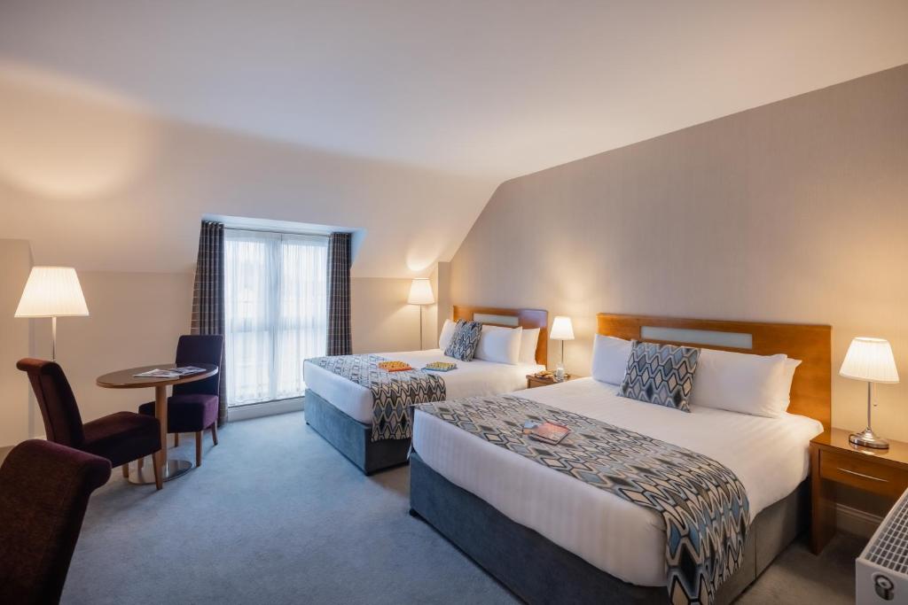um quarto de hotel com duas camas e uma mesa em Raheen Woods Hotel em Athenry