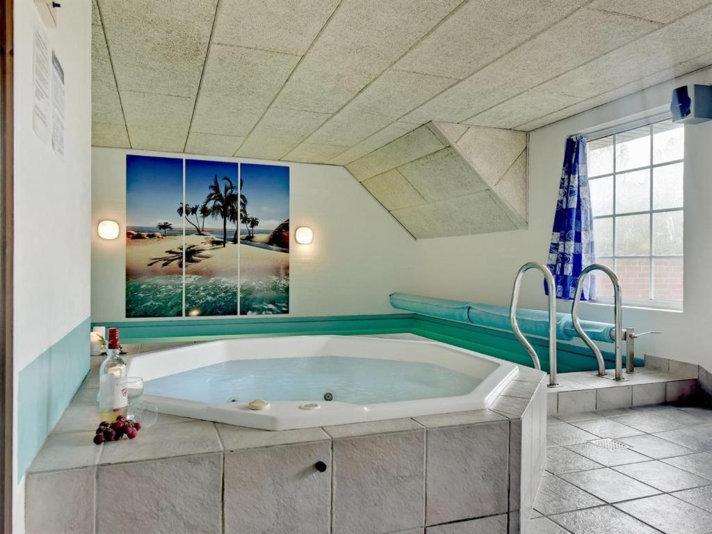 La salle de bains est pourvue d'une grande baignoire et d'une peinture murale. dans l'établissement Holiday Home Joona - 12km from the sea in Western Jutland by Interhome, à Oksbøl