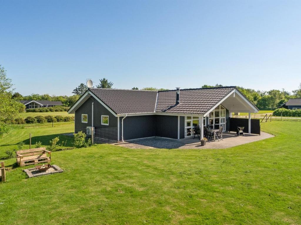 une maison noire avec une grande cour avec une pelouse dans l'établissement Holiday Home Eicke - 12km from the sea in Western Jutland by Interhome, à Oksbøl