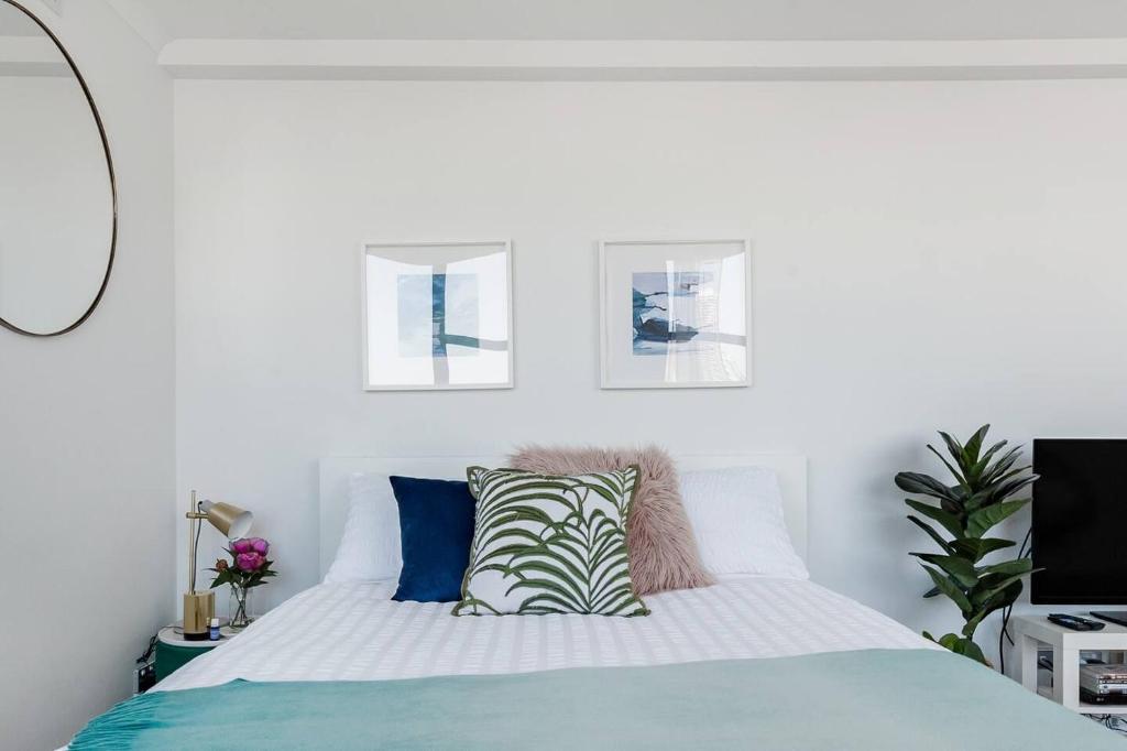 a white bedroom with a bed with blue pillows at Abwechslungsreiche Unterkunft mit charmanten Flair in Hilden