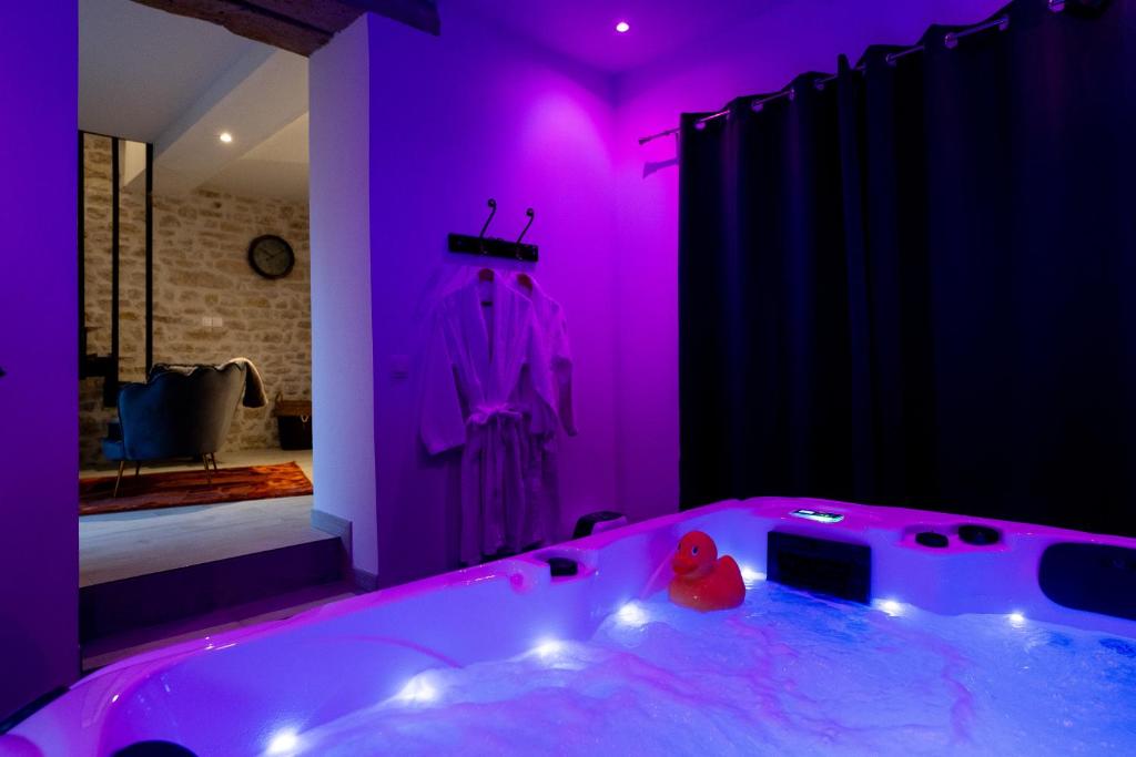 La salle de bains est pourvue d'une grande baignoire avec un éclairage violet. dans l'établissement Jacuzzi- Chambre Secrète- Love Room- Une Pause à Deux, à Château-Landon