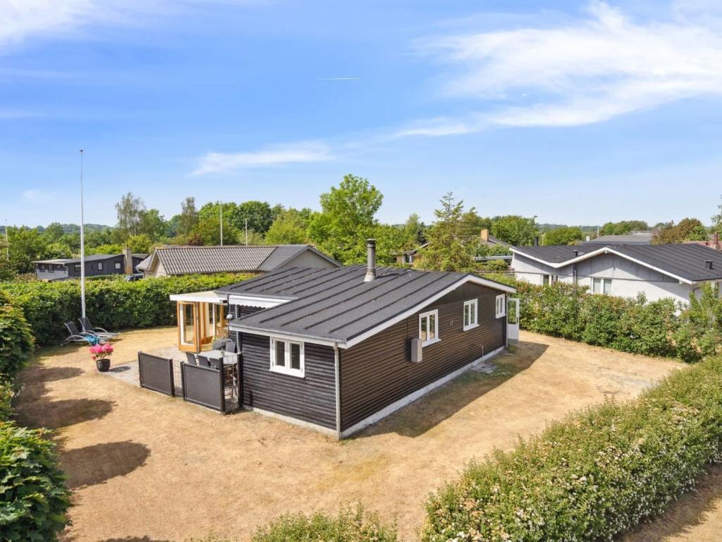 una pequeña casa con un techo negro en un patio en Holiday Home Sari - 250m from the sea in SE Jutland by Interhome, en Sønderby