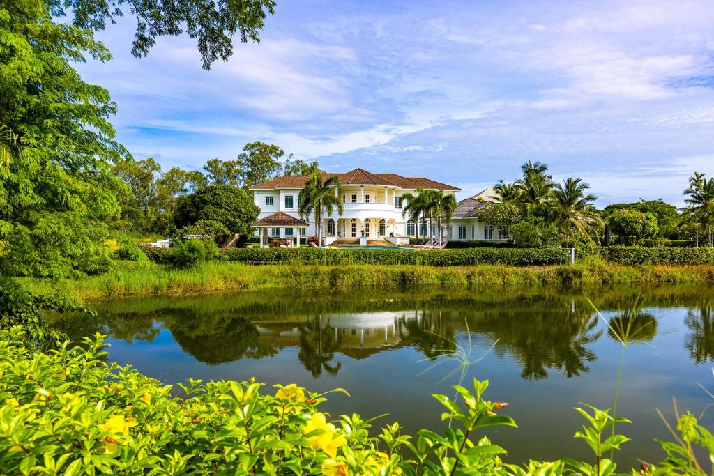 a house with a pond in front of it at The White House, Palm Hills Golf and Country Club in Ban Nong Sai
