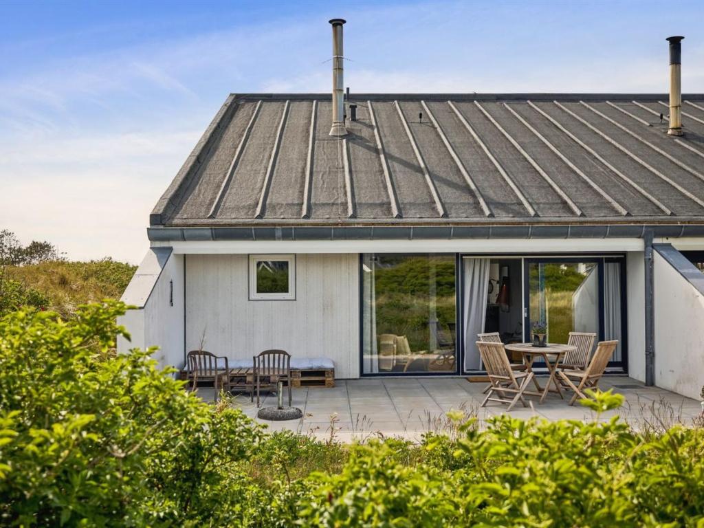 Dieses weiße Haus verfügt über eine Terrasse mit einem Tisch und Stühlen. in der Unterkunft Apartment Kaapo - 1km from the sea in NW Jutland by Interhome in Blokhus