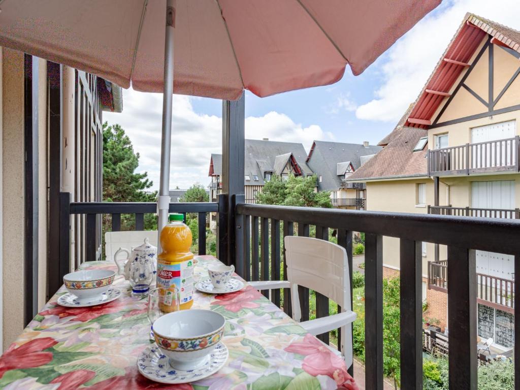 - une table sur un balcon avec un parasol dans l'établissement Apartment Le Clos Mathilde-21 by Interhome, à Cabourg