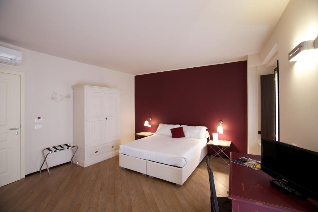 1 dormitorio con cama blanca y pared roja en Hotel Leon D'Oro, en Mantua