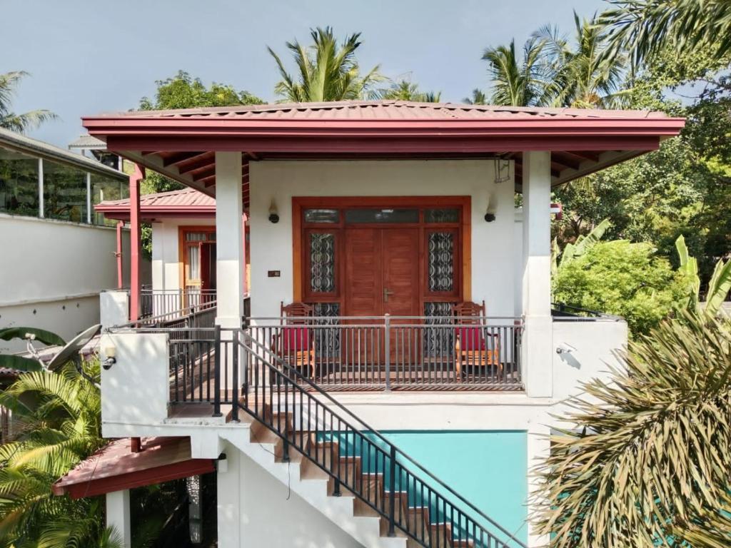 a house with a red door and a balcony at Home Stay Resort in Nilaveli