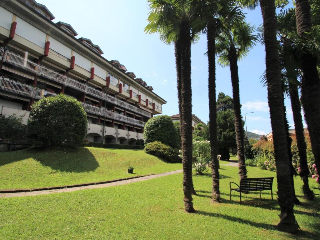 um parque com um banco e palmeiras em frente a um edifício em Apartment Liberty by Interhome em Luino