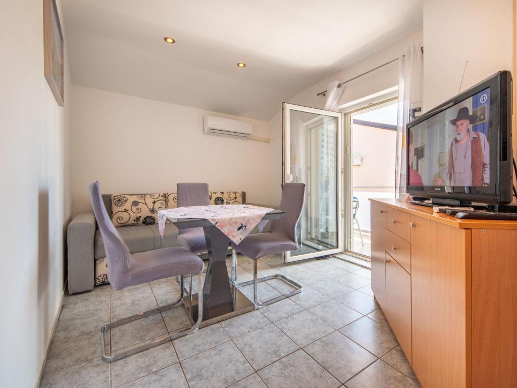 ein Wohnzimmer mit einem Tisch, Stühlen und einem TV in der Unterkunft Apartment Fruk-3 by Interhome in Jadranovo