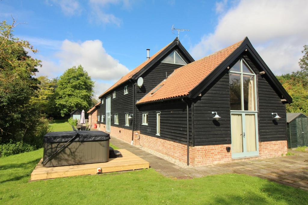 a black house with a trash can in front of it at Old Oak Barn - Beautiful barn conversion with wonderful Jacuzzi hot tub in Stowmarket
