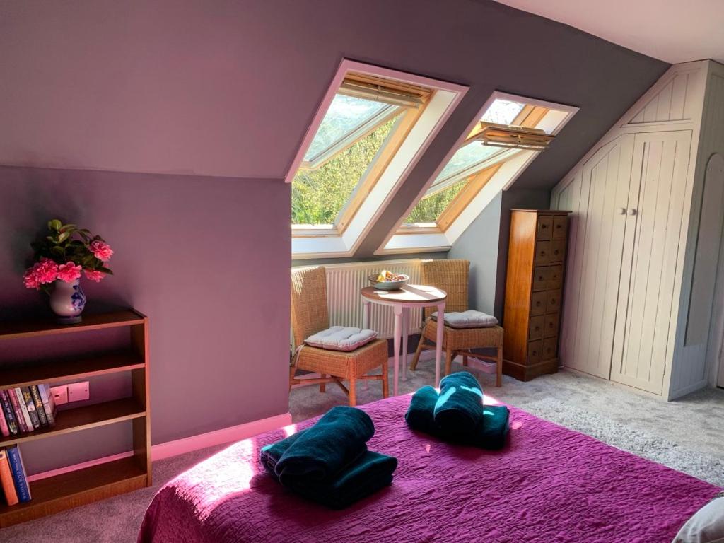 a bedroom with a purple room with a bed and a table at Silverspring Farm En suite in Constantine