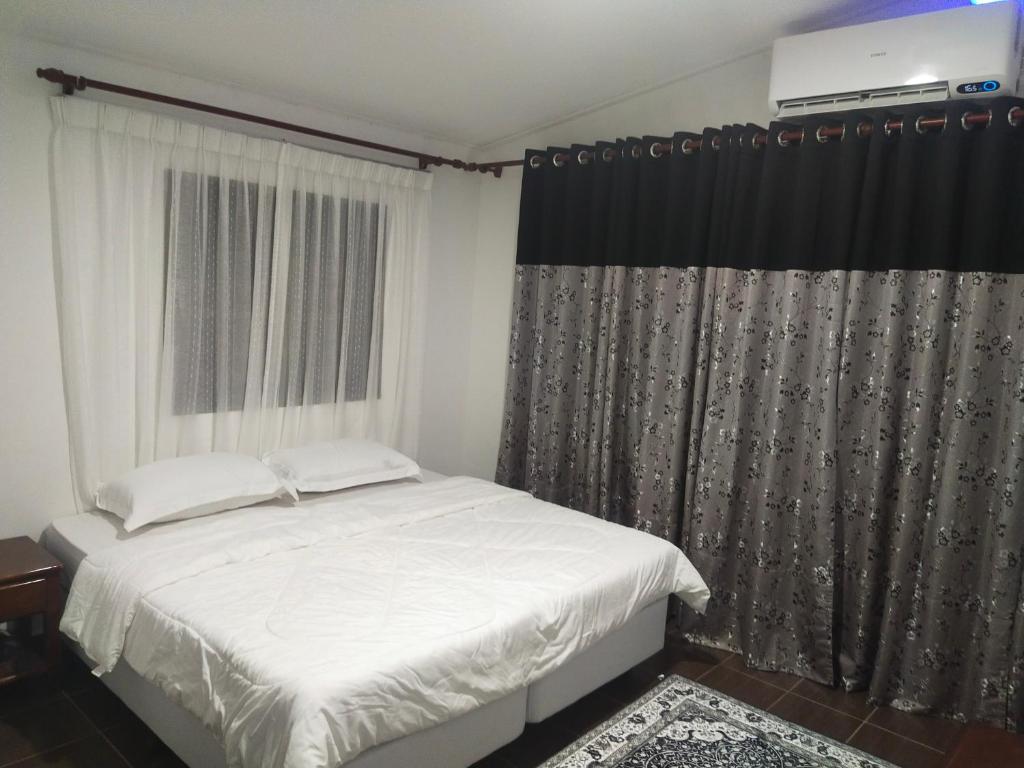 Un dormitorio con una cama blanca y una ventana. en RoomStay Noraz, en Kampong Baharu
