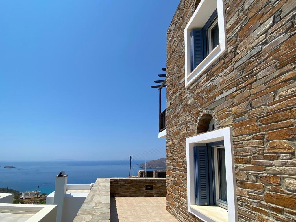 a stone house with blue shutters and a view of the ocean at andros prive suites in Kipri