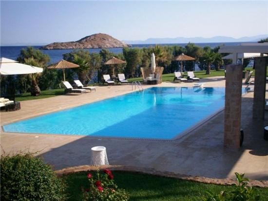 a large blue swimming pool with chairs and umbrellas at MEDOUSA VILLA in Porto Rafti