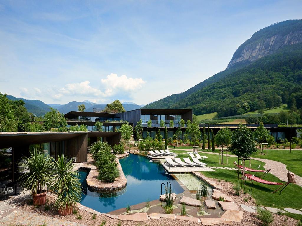 a resort with a pool and mountains in the background at Manna Resort in Montagna