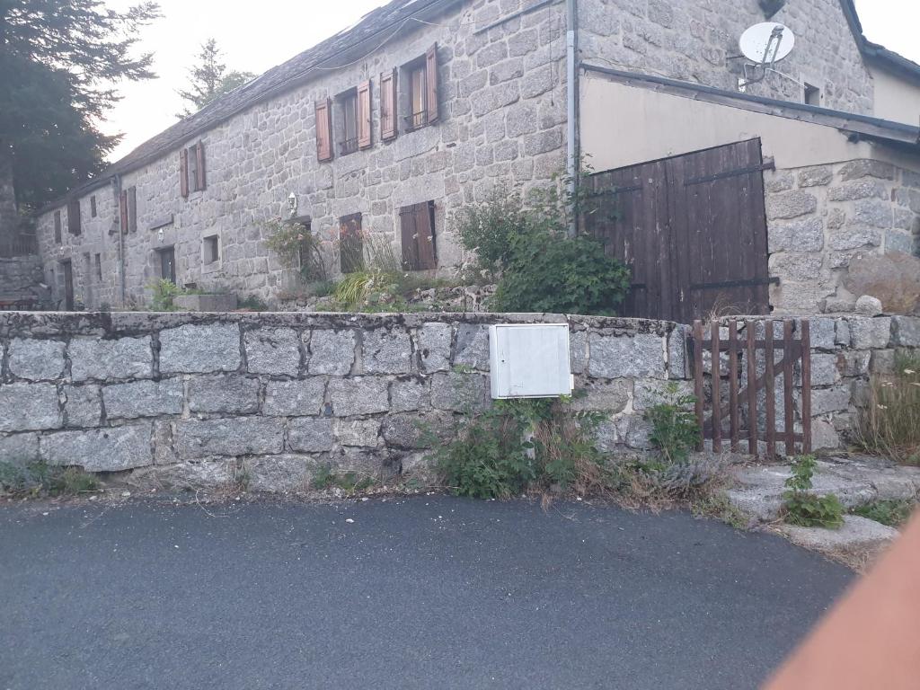 un antiguo edificio de piedra con una puerta y una valla en Chambre d'hôtes Aubrac Nasbinals a75 